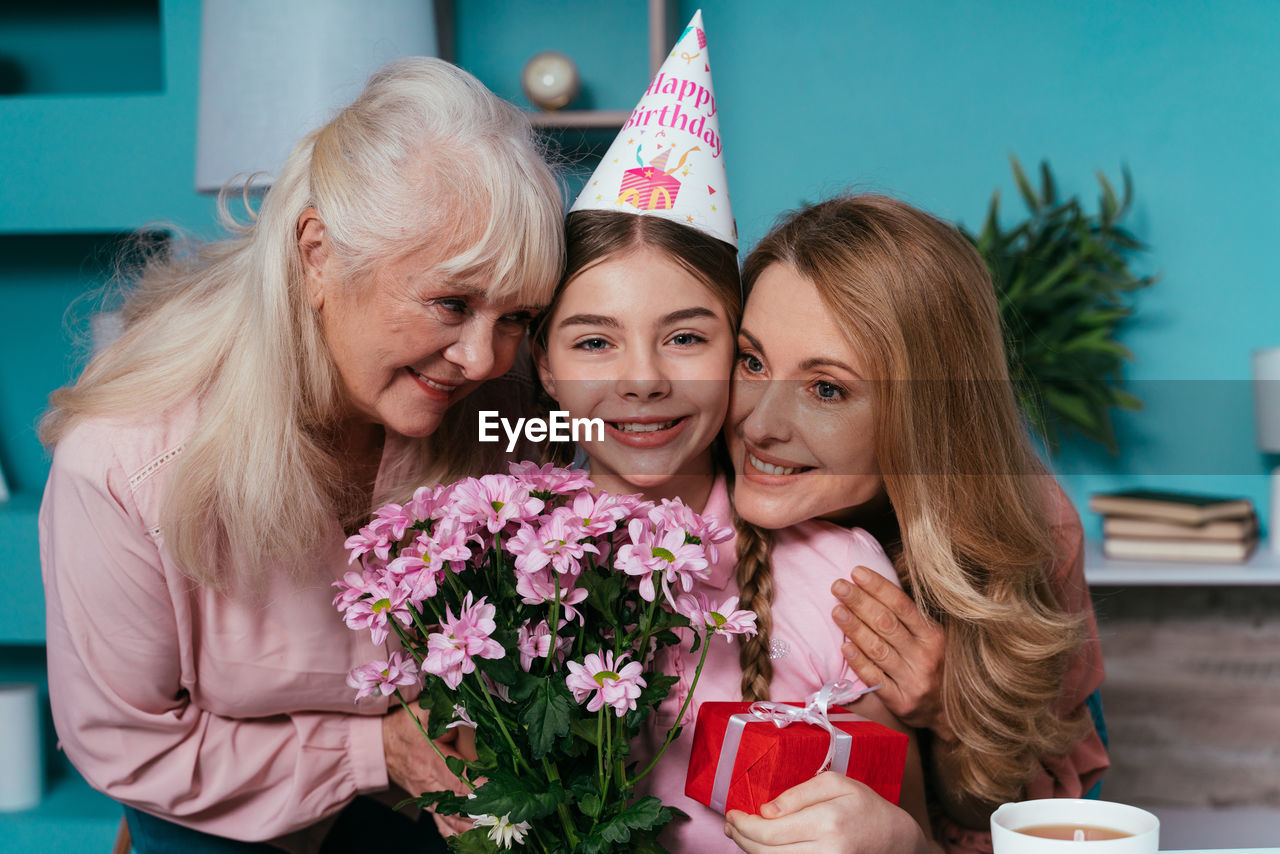 Smiling mother and grandmother embracing girl at home