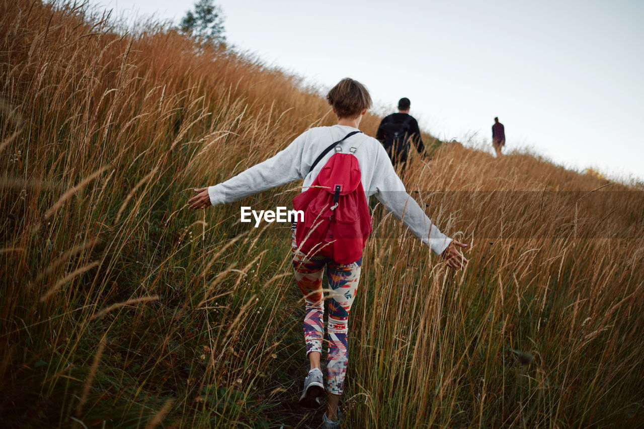 Rear view of woman wearing backpack on field against clear sky