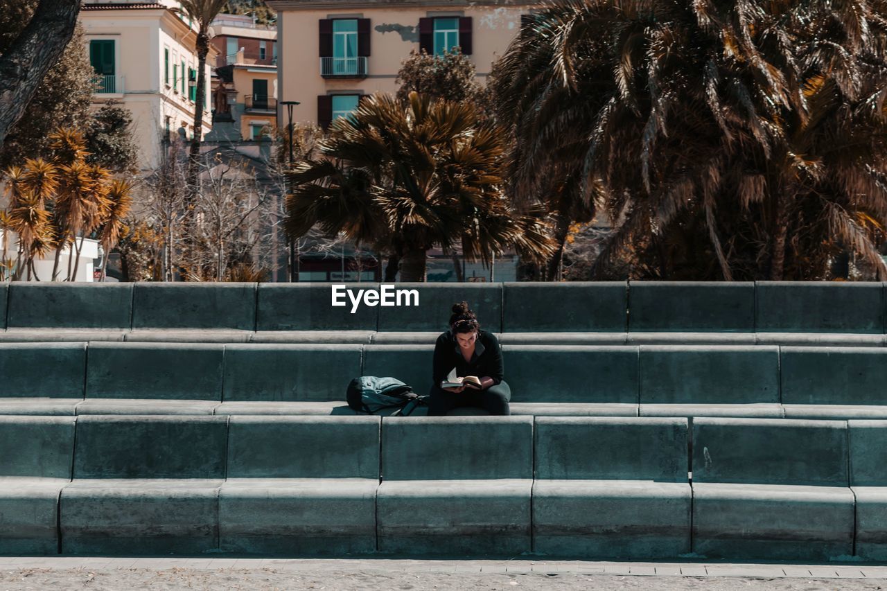 MAN SITTING ON BENCH AGAINST CITY