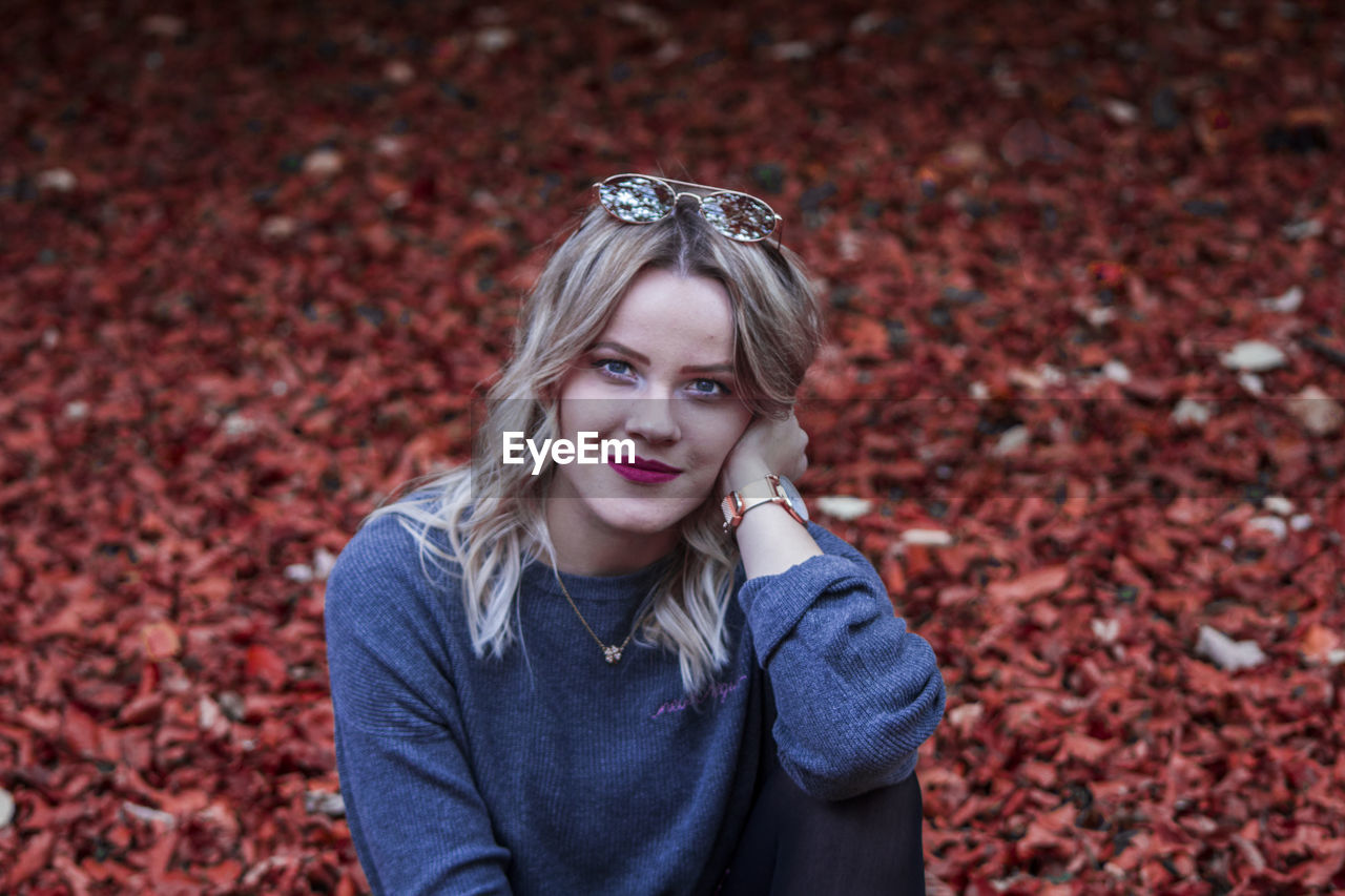 Portrait of young woman against autumn leaves
