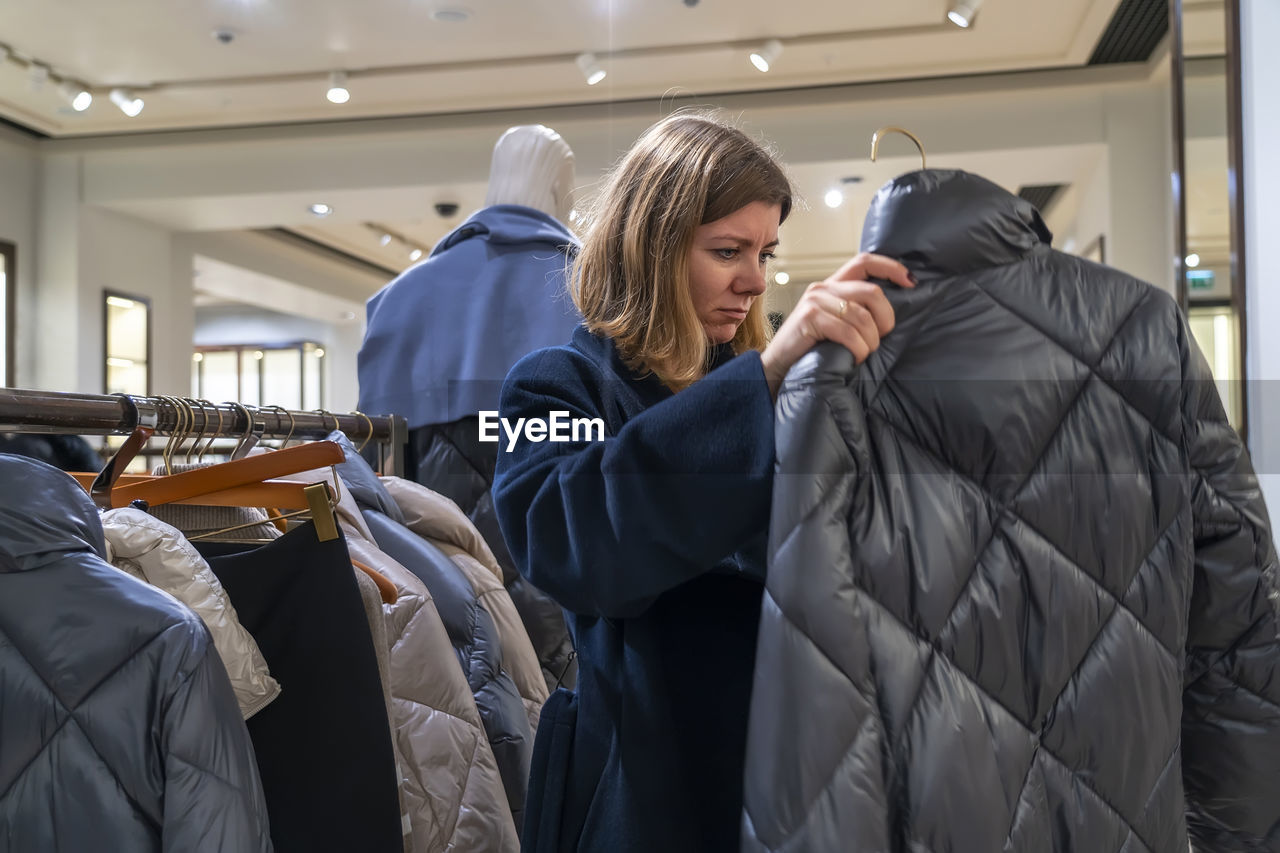 Woman checking padded jacket in clothing store
