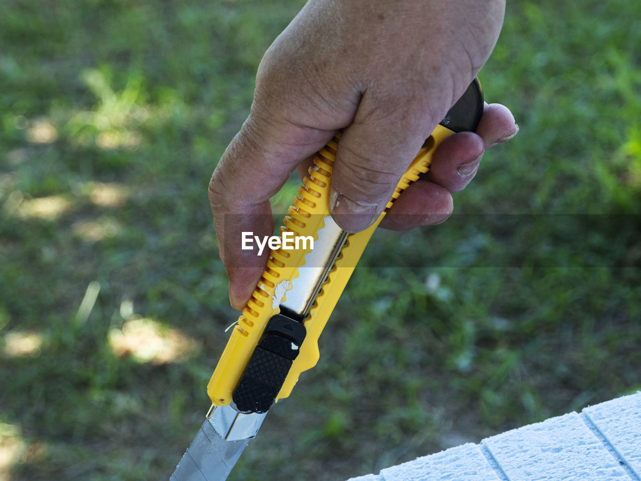 Close-up of hand holding yellow utility knife