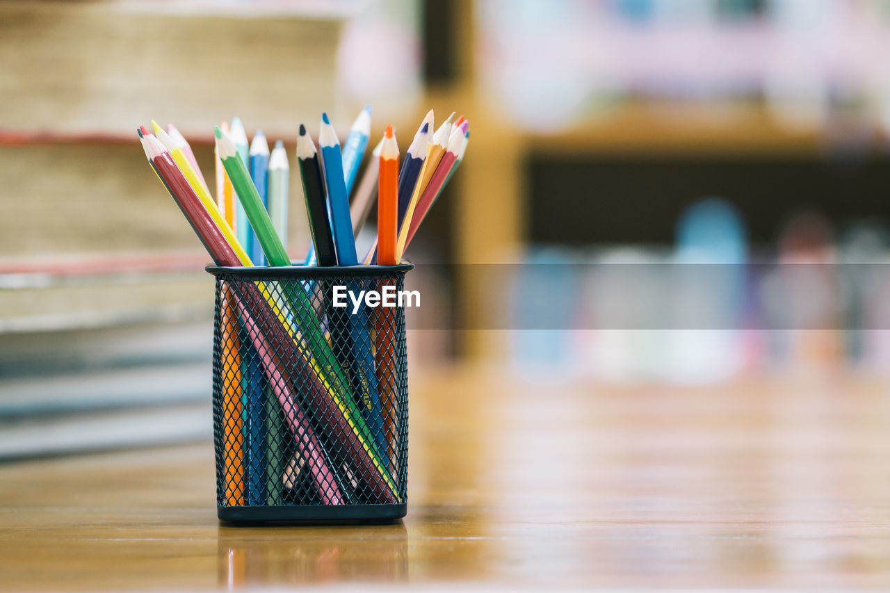 Close-up of colored pencils in desk organizer on table