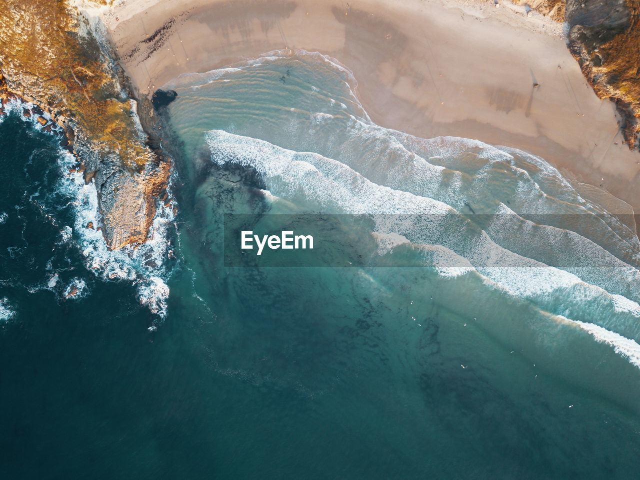 High angle view of sea shore with surfers and waves