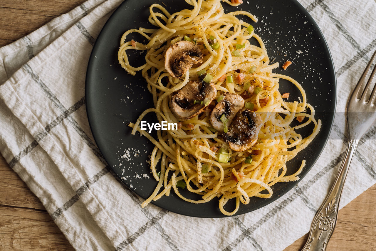 Spaghetti pasta with champignon mushrooms sprinkled with cheese parmesan and green onions