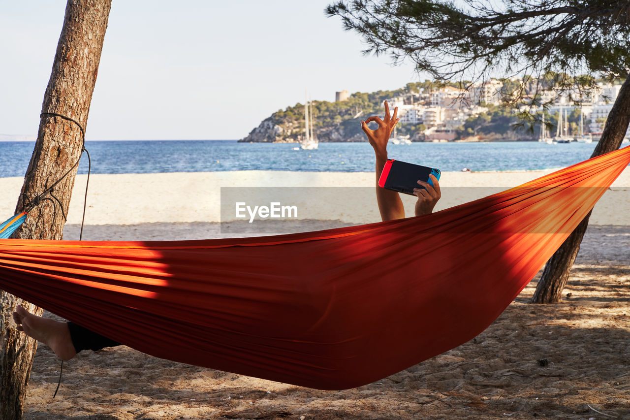 MAN ON HAMMOCK BY SEA AGAINST SKY