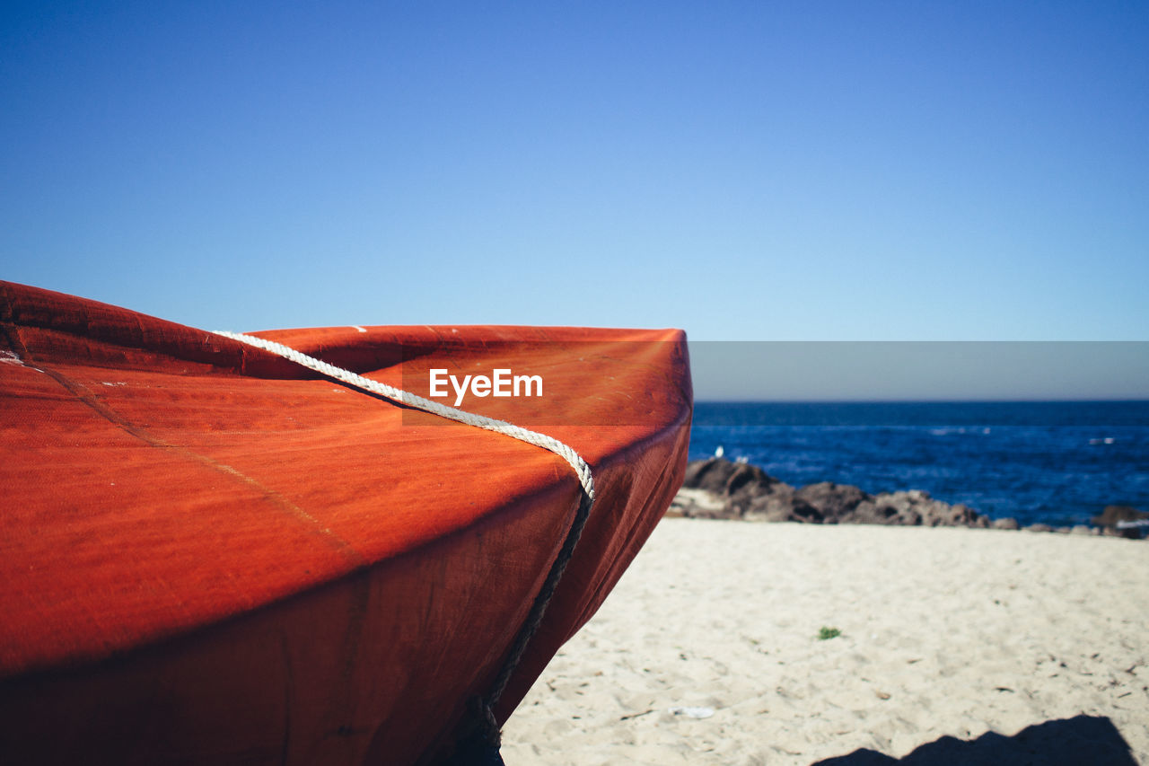 Cropped image of boat at beach against clear blue sky