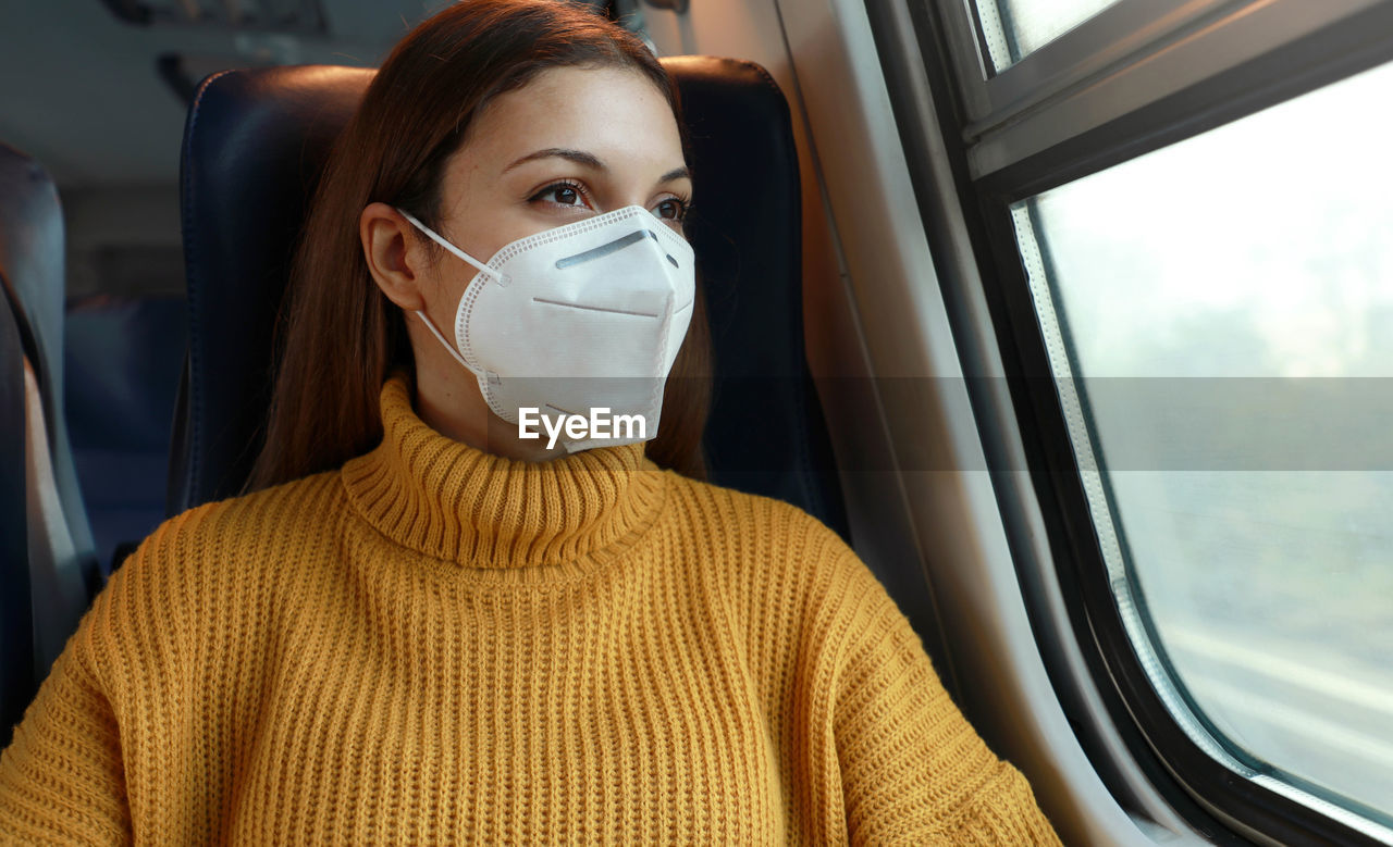 Young woman in mask sitting at bus