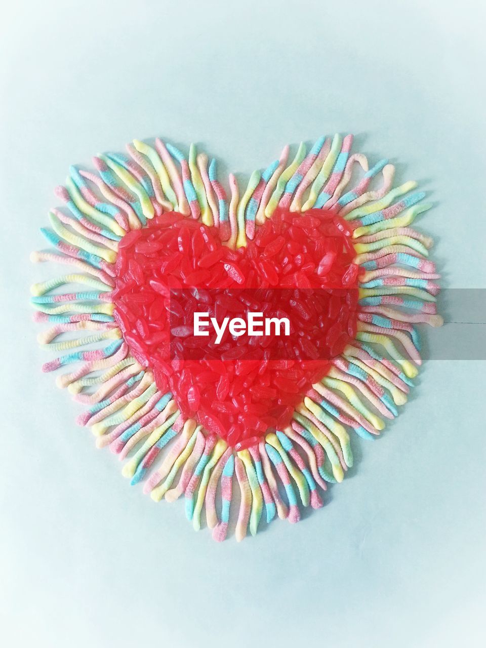 High angle view of heart made of candies against white background