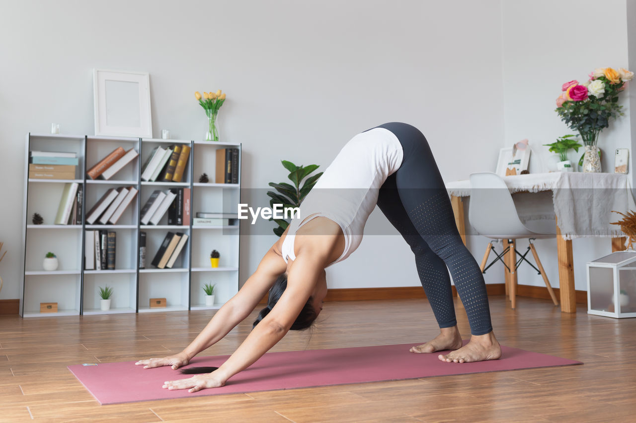 WOMAN SITTING ON HARDWOOD FLOOR IN ROOM