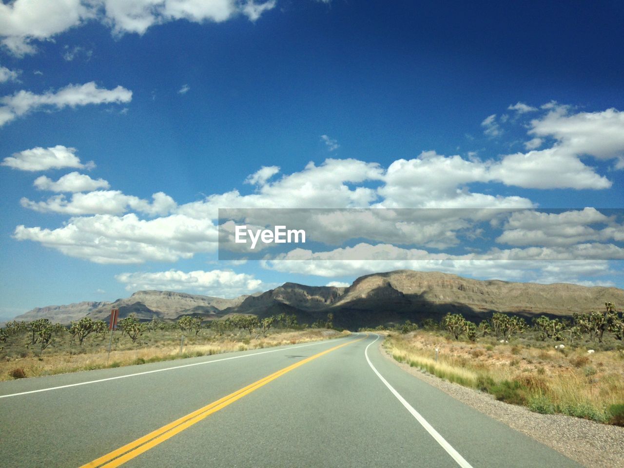 Road by mountains against blue sky