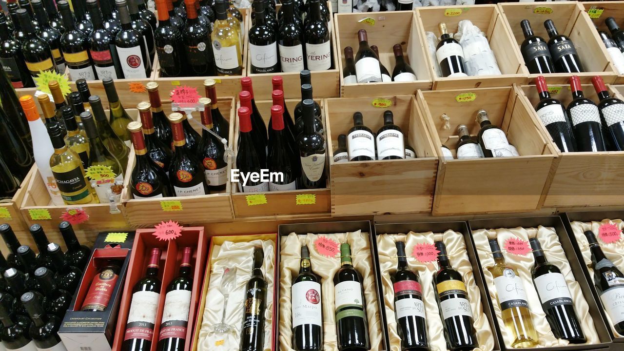 CLOSE-UP OF BOTTLES ON SHELF AT MARKET STALL