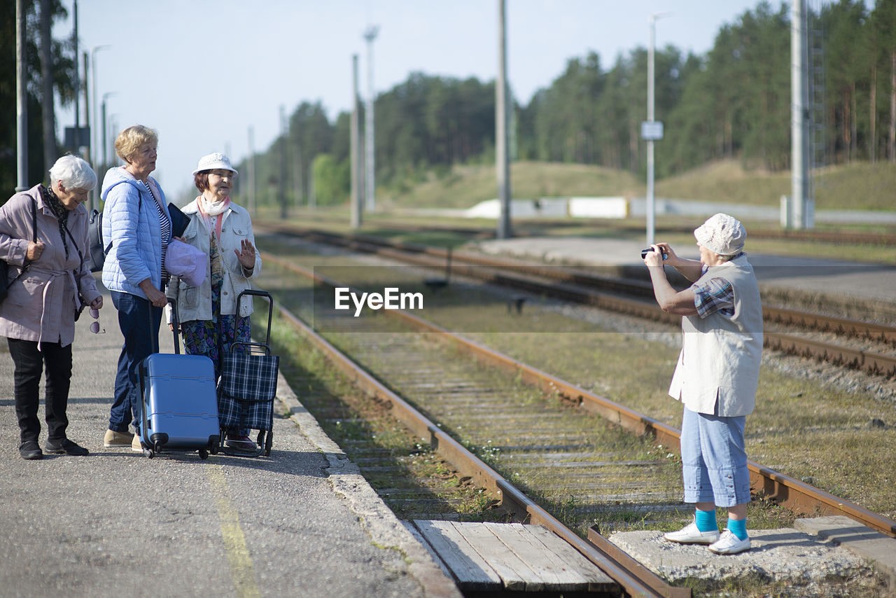 Senior women take a photo on a platform waiting for a train to travel during a covid-19 pandemic