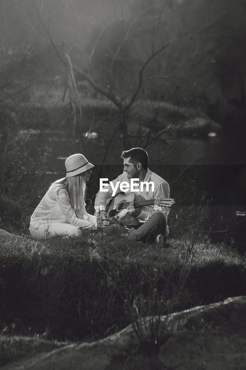 Couple sitting on grass in forest