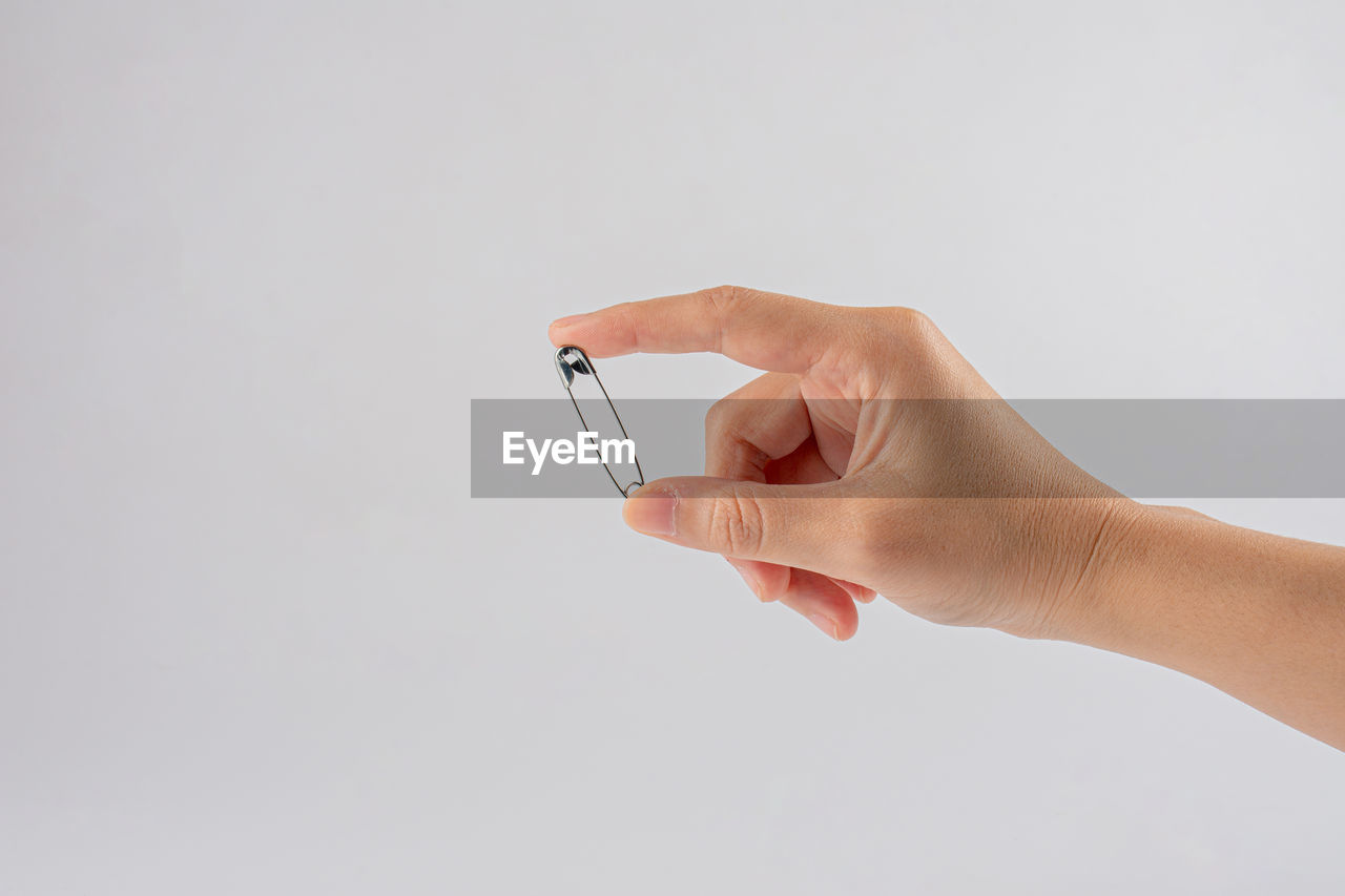 CLOSE-UP OF HAND HOLDING CAMERA AGAINST WHITE BACKGROUND