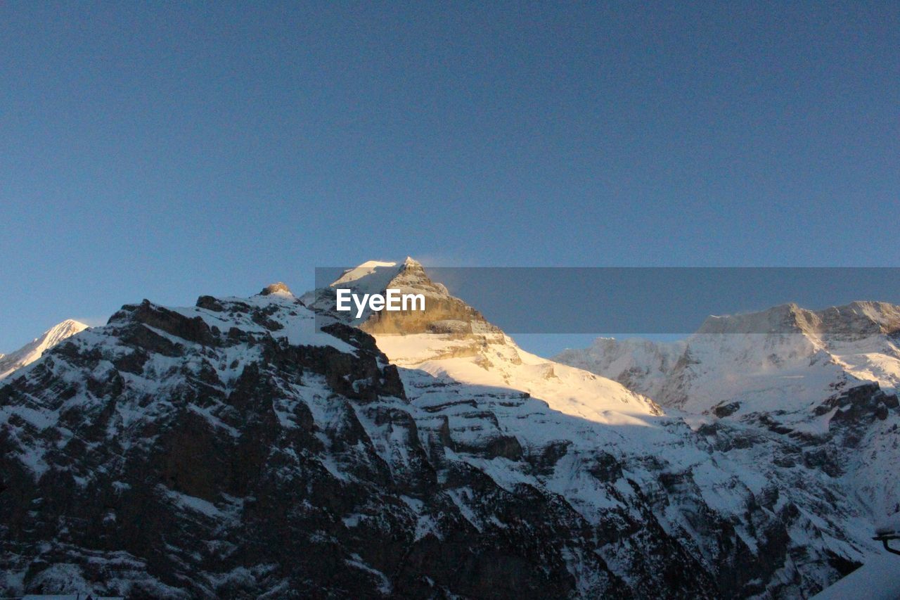 Low angle view of snow covered mountain against clear sky