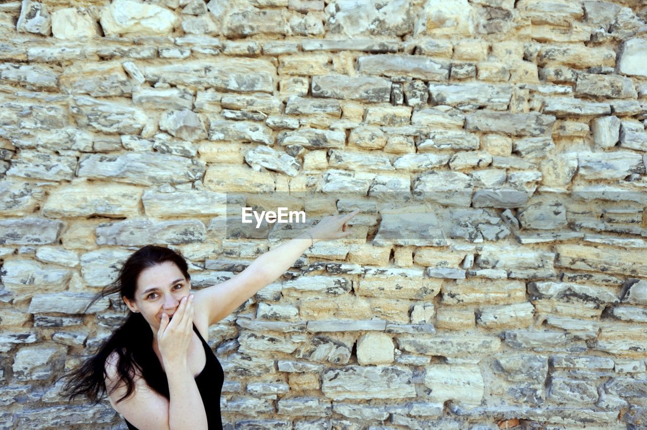 Portrait of woman standing against old wall