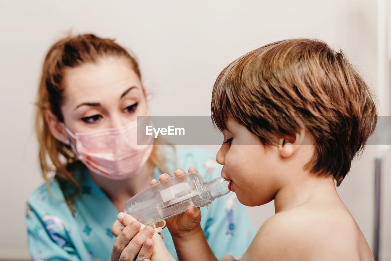 Little kid using inhaler in clinic during check up