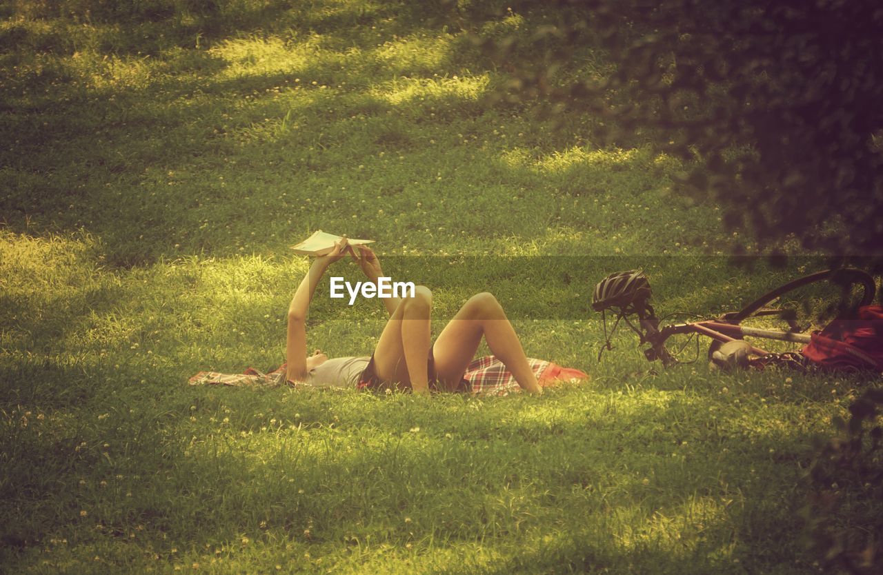 Woman by bicycle relaxing on grassy field