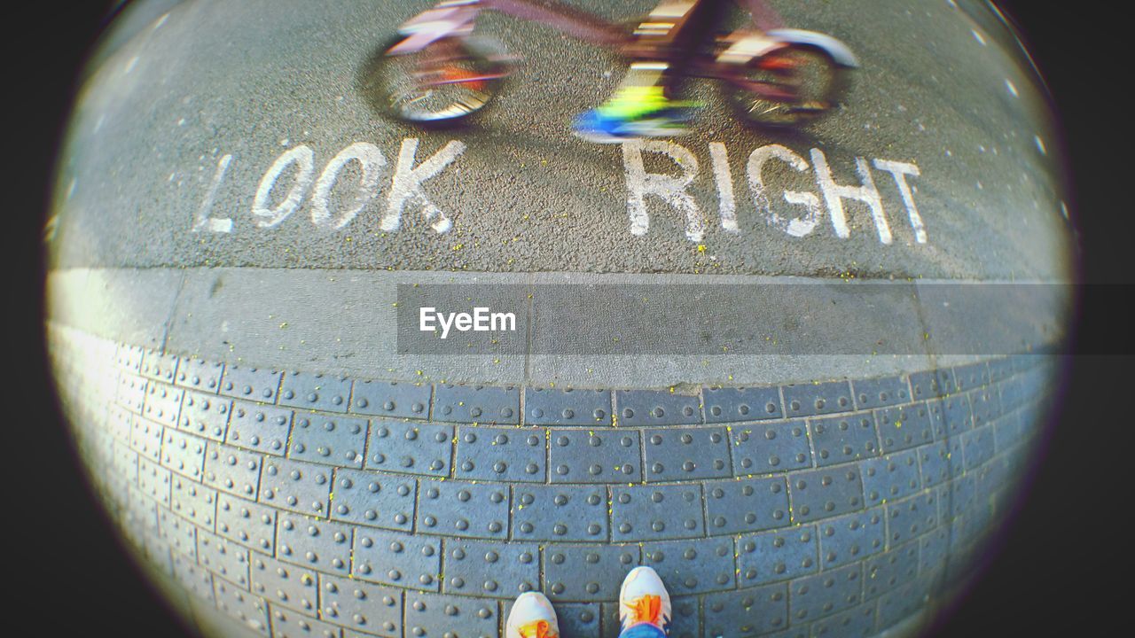 Text on street with person riding bicycle seen through hole