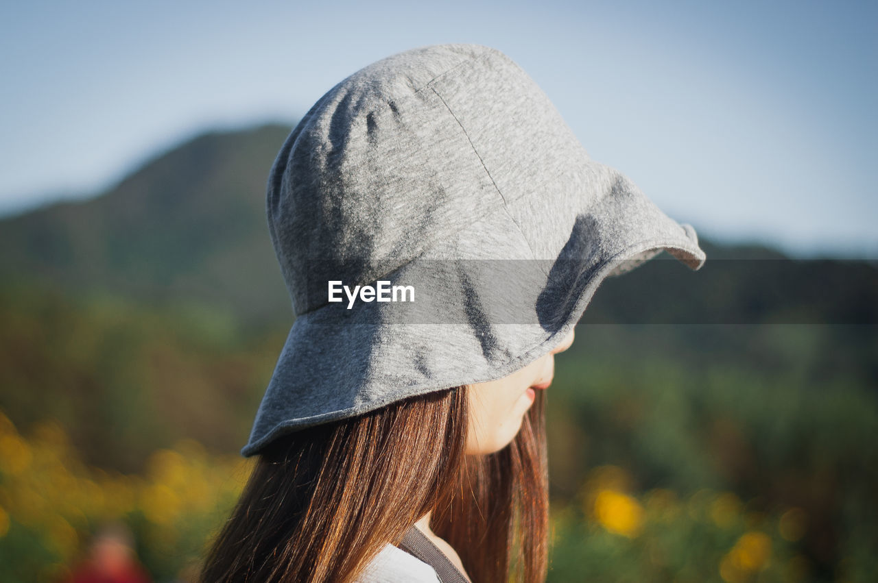Side view of woman wearing hat against sky