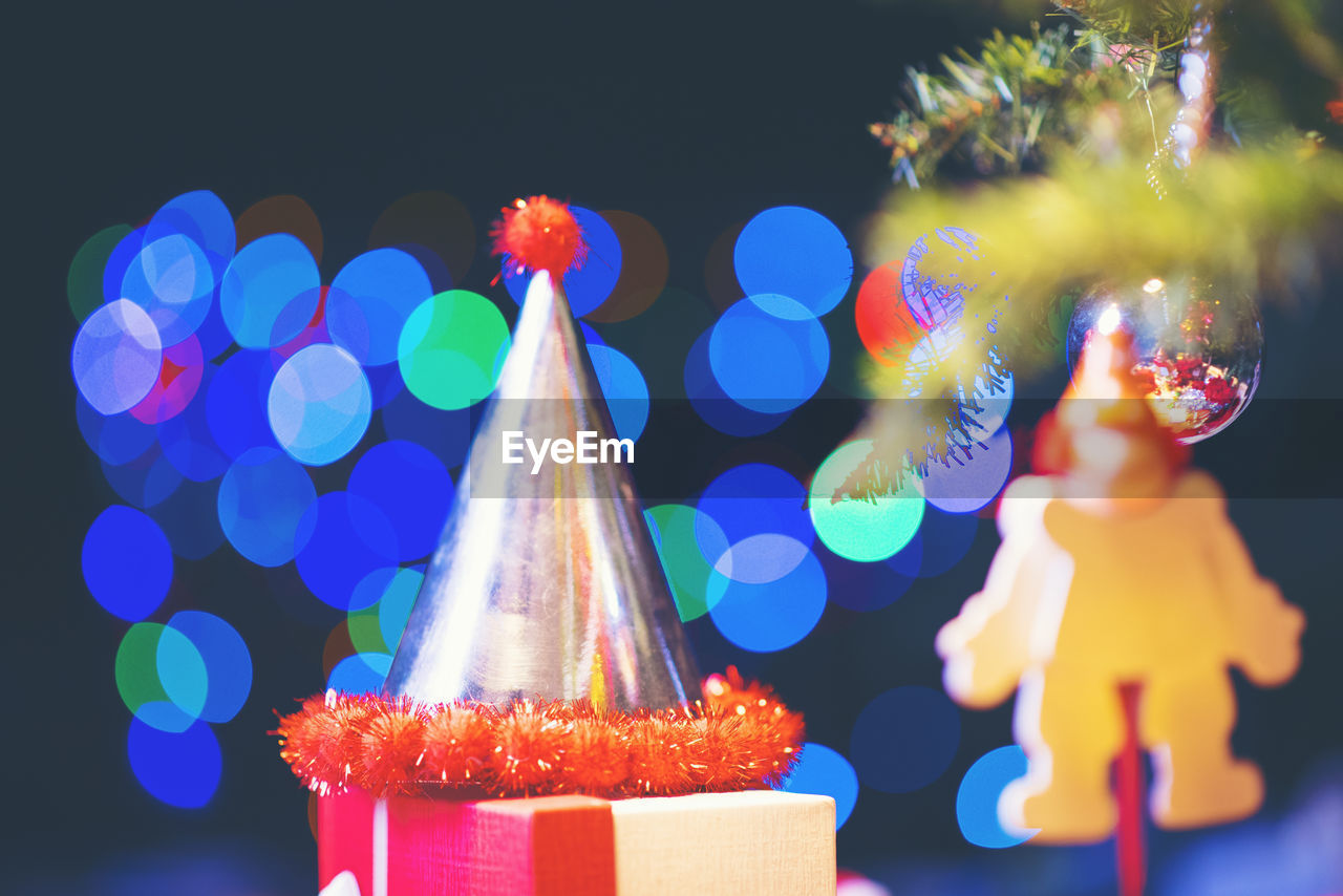 Close-up of party hat against illuminated christmas tree at night