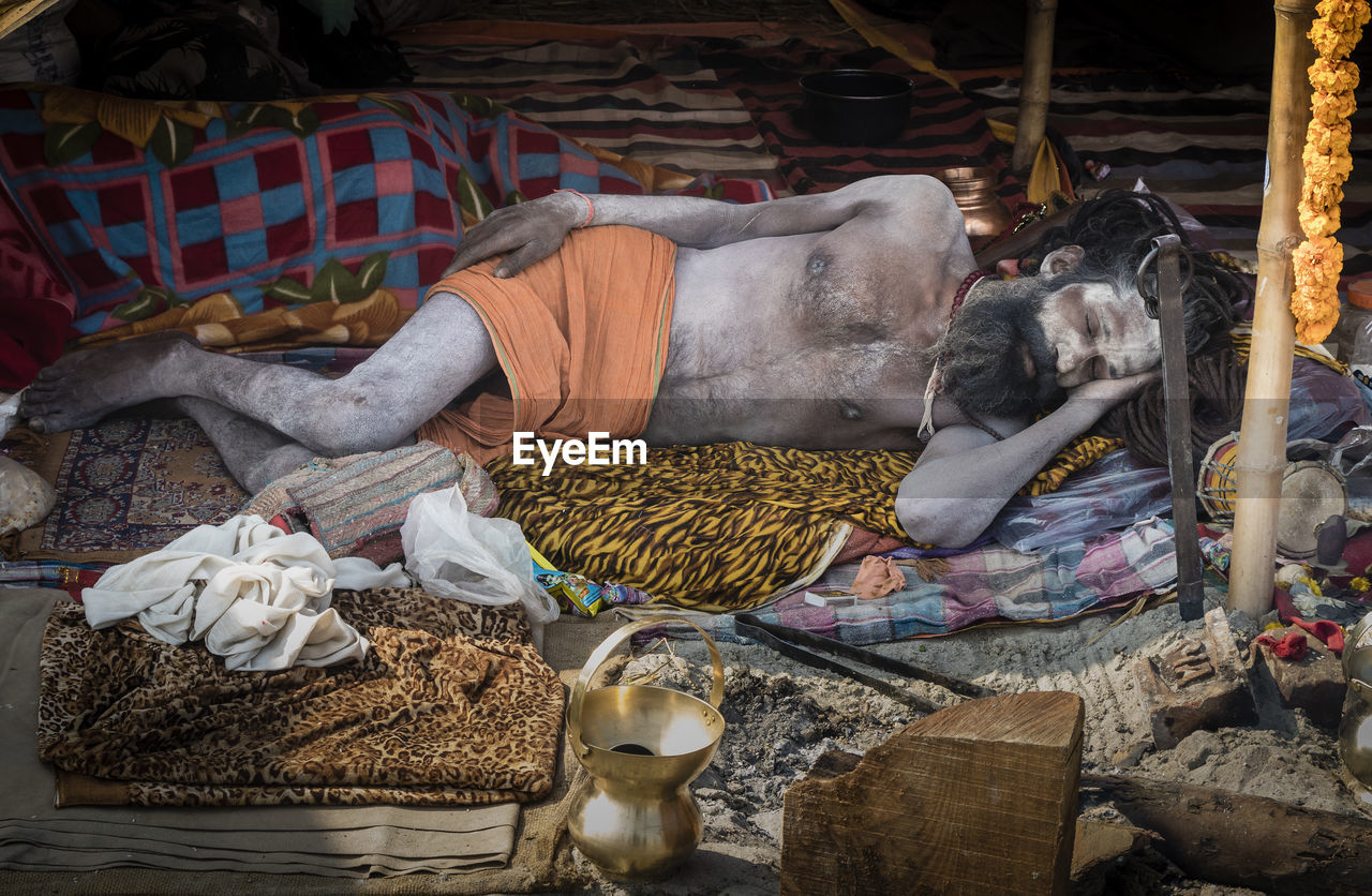 Full length of sadhu sleeping in traditional clothing outdoors