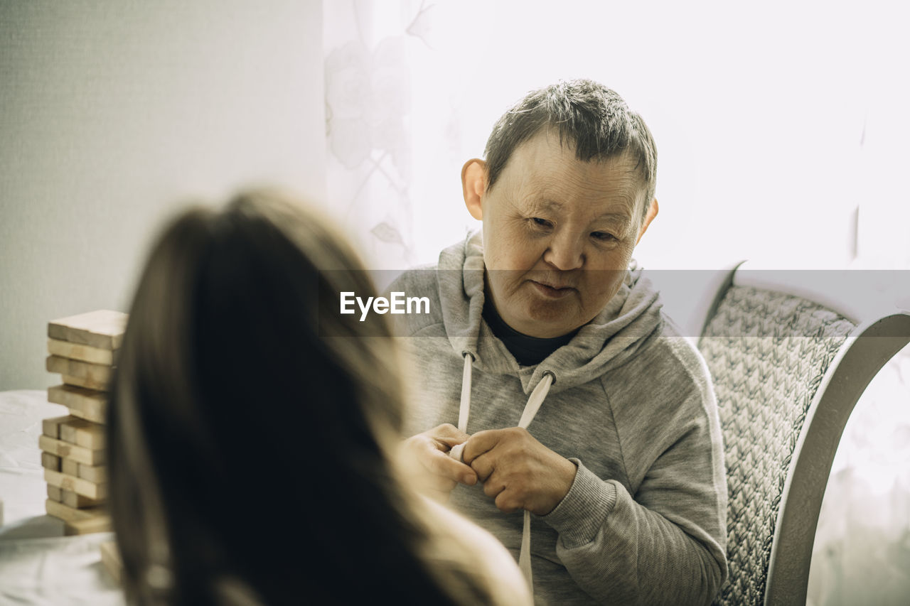 An elderly woman with down syndrome, accompanied by an assistant who supports her