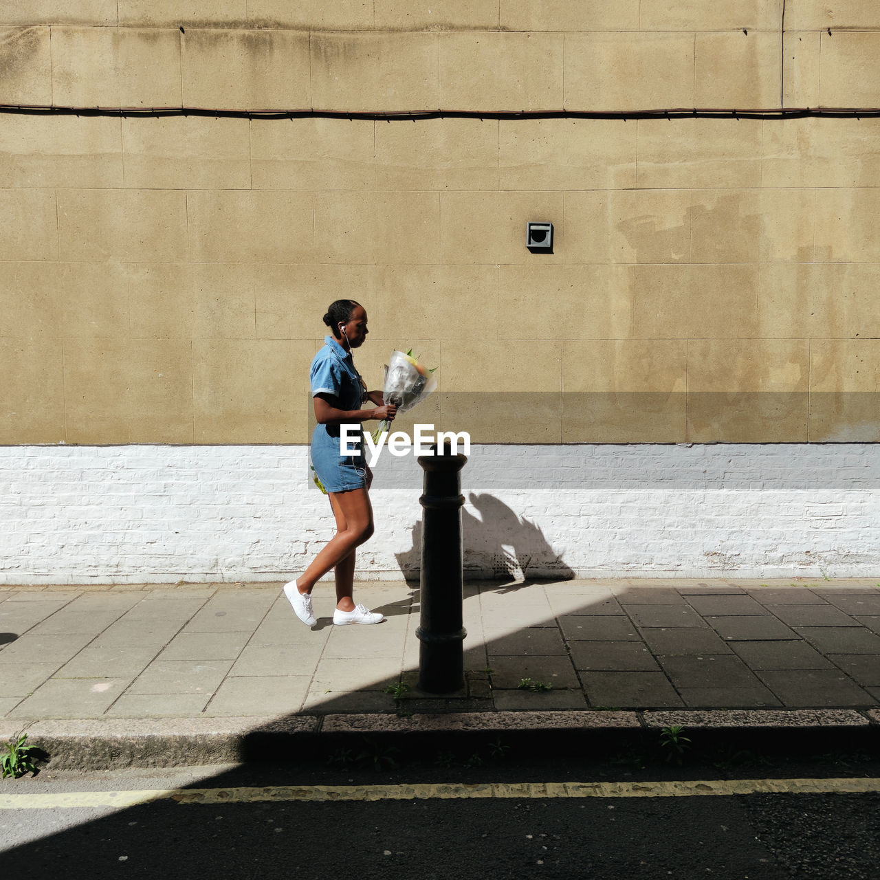 FULL LENGTH OF MAN WALKING ON FOOTPATH AGAINST WALL