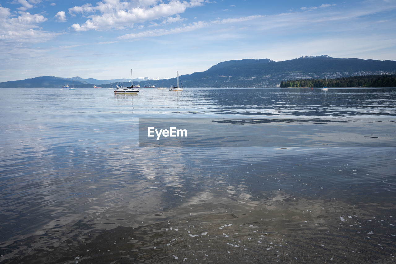 Calm sea with boats and mountains in backdrop, shot in vancouver, british columbia, canada