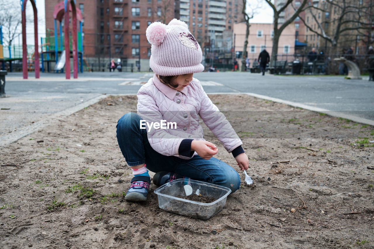 Girl digging in the dirt on the playground on a foggy fall day