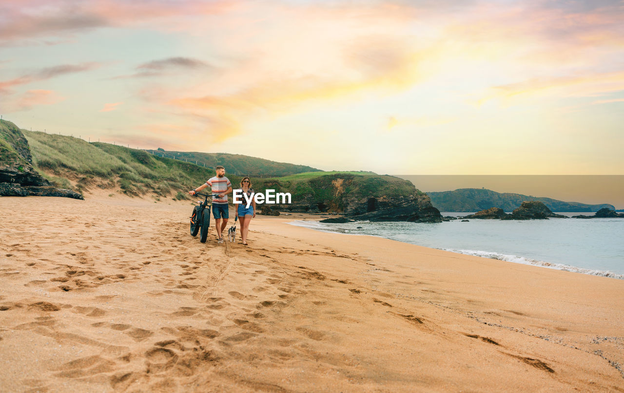 Couple with a fat bike taking a walk on the beach