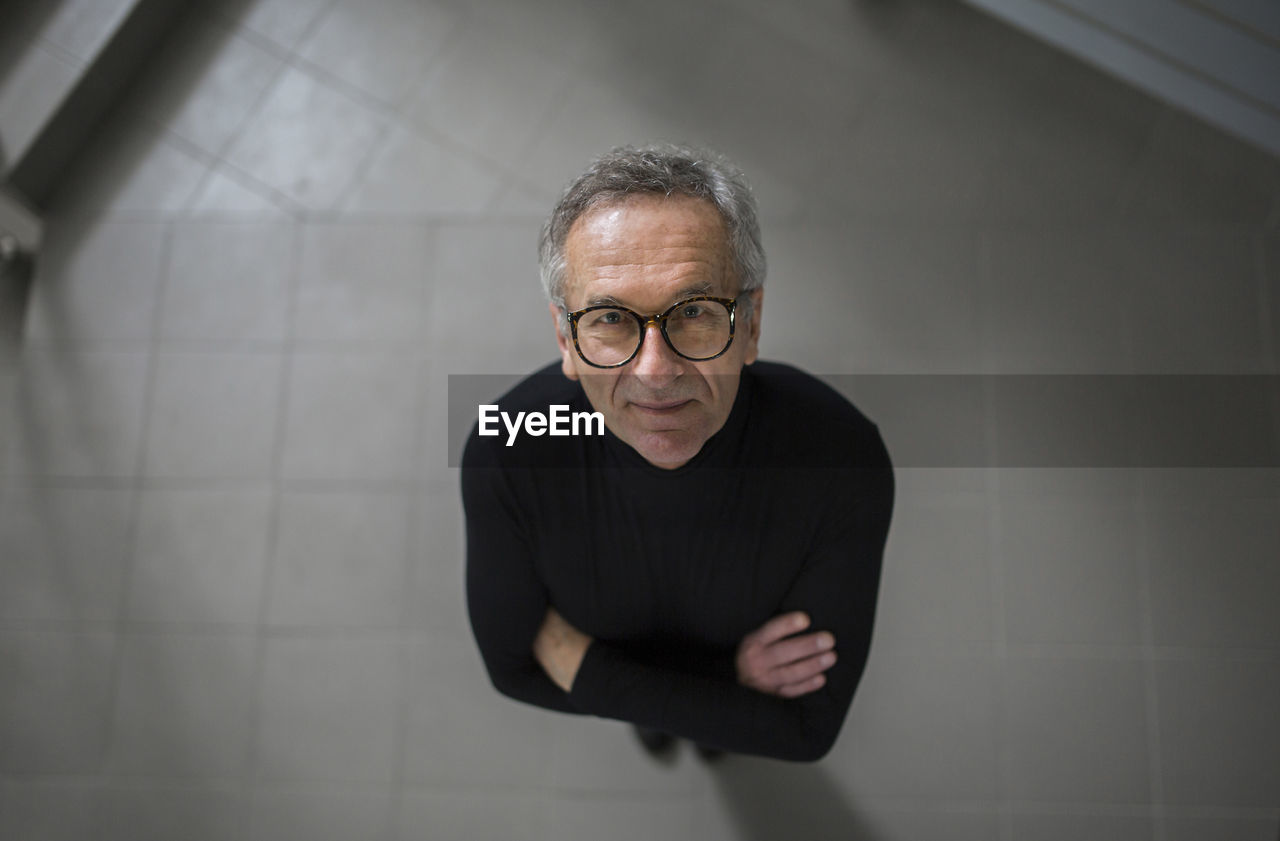 Smiling senior businessman looking up on office hallway