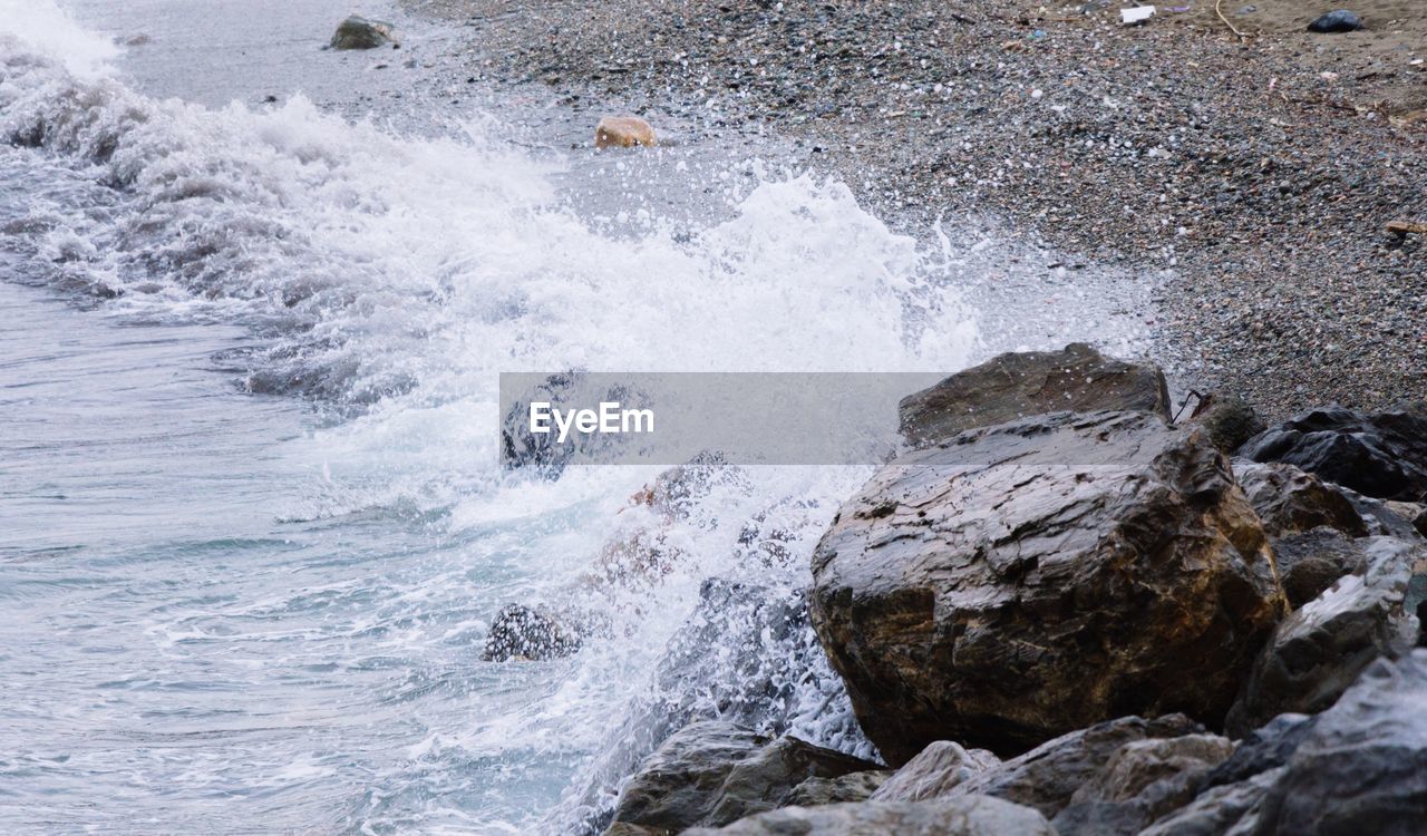 High angle view of waves splashing on rocks at beach