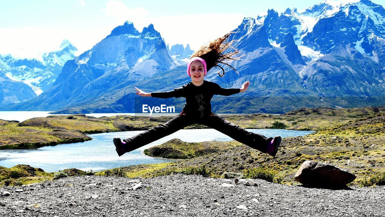 Full length of girl jumping in front of mountain