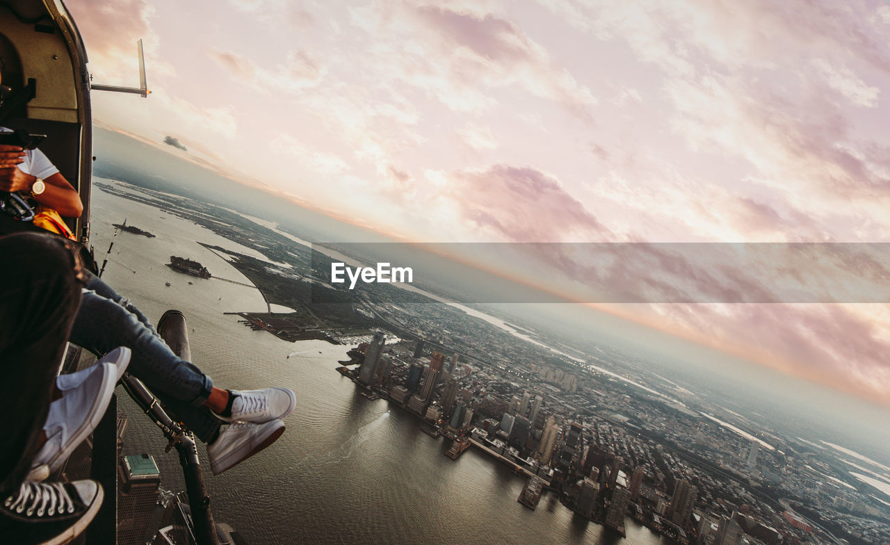 Low section of man sitting in helicopter over buildings in city