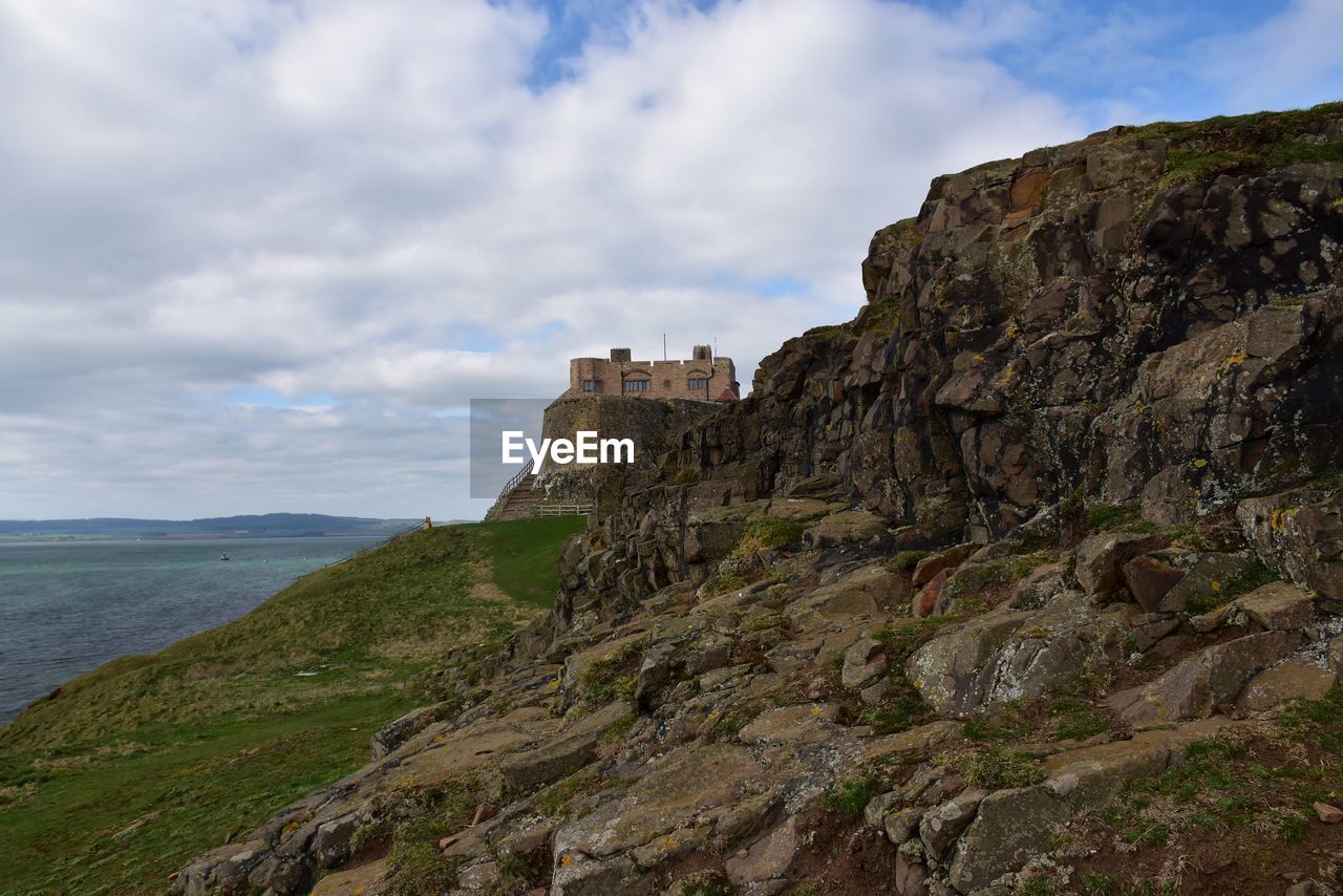 Scenic view of cliff by sea against sky