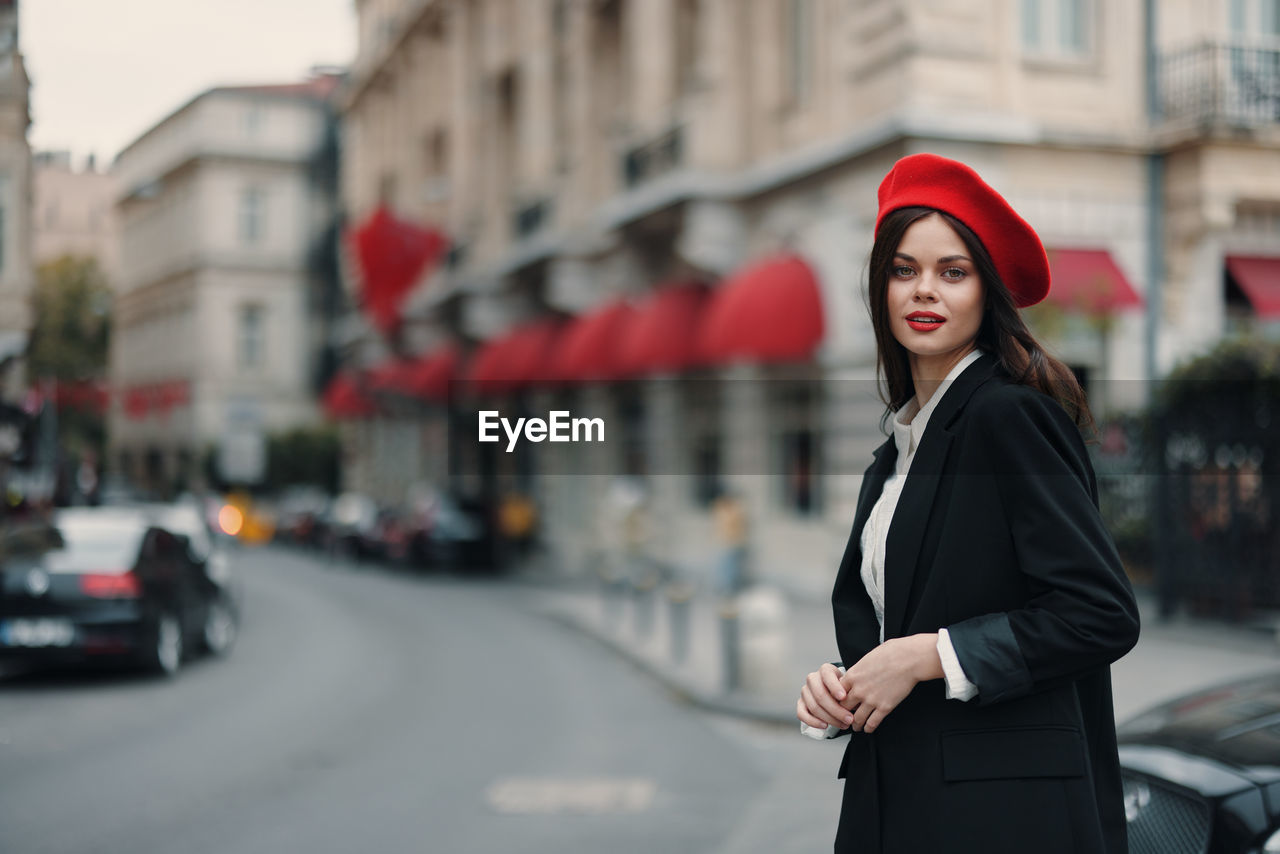 portrait of young woman standing against buildings in city