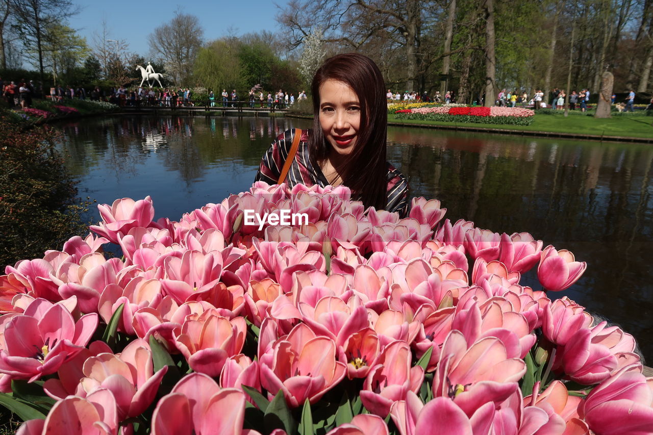 Portrait of woman with pink flowers against lake