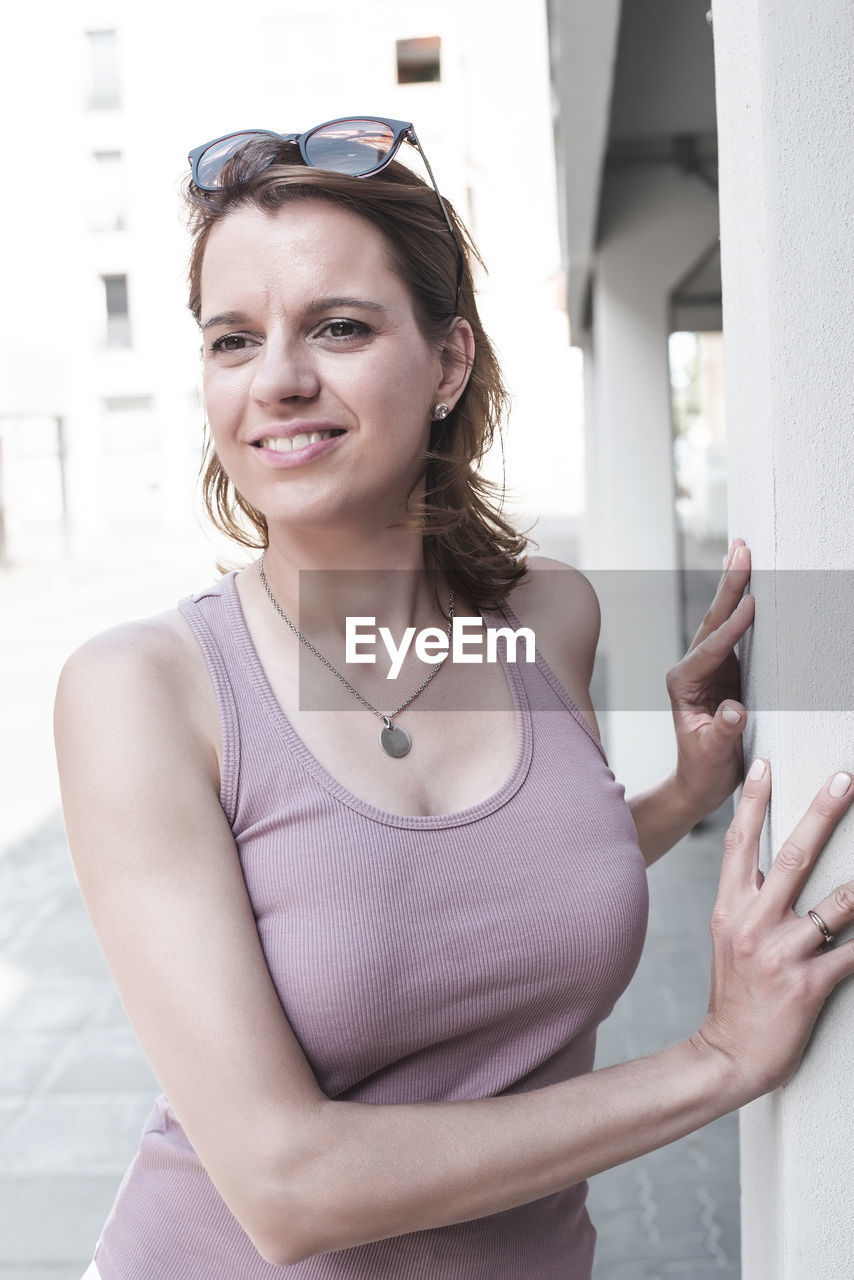 portrait of smiling young woman looking away while standing outdoors