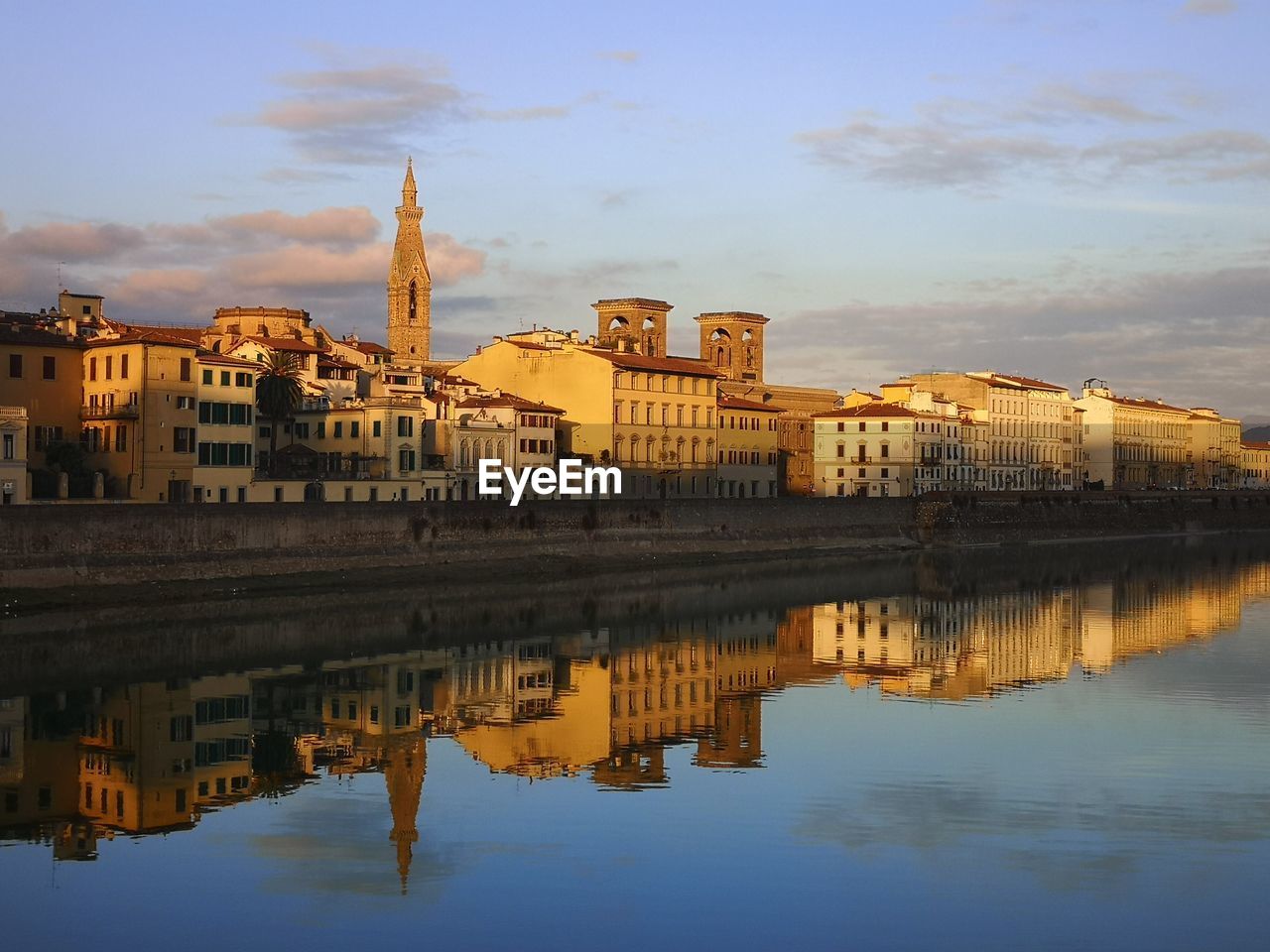 REFLECTION OF BUILDINGS IN RIVER AGAINST SKY