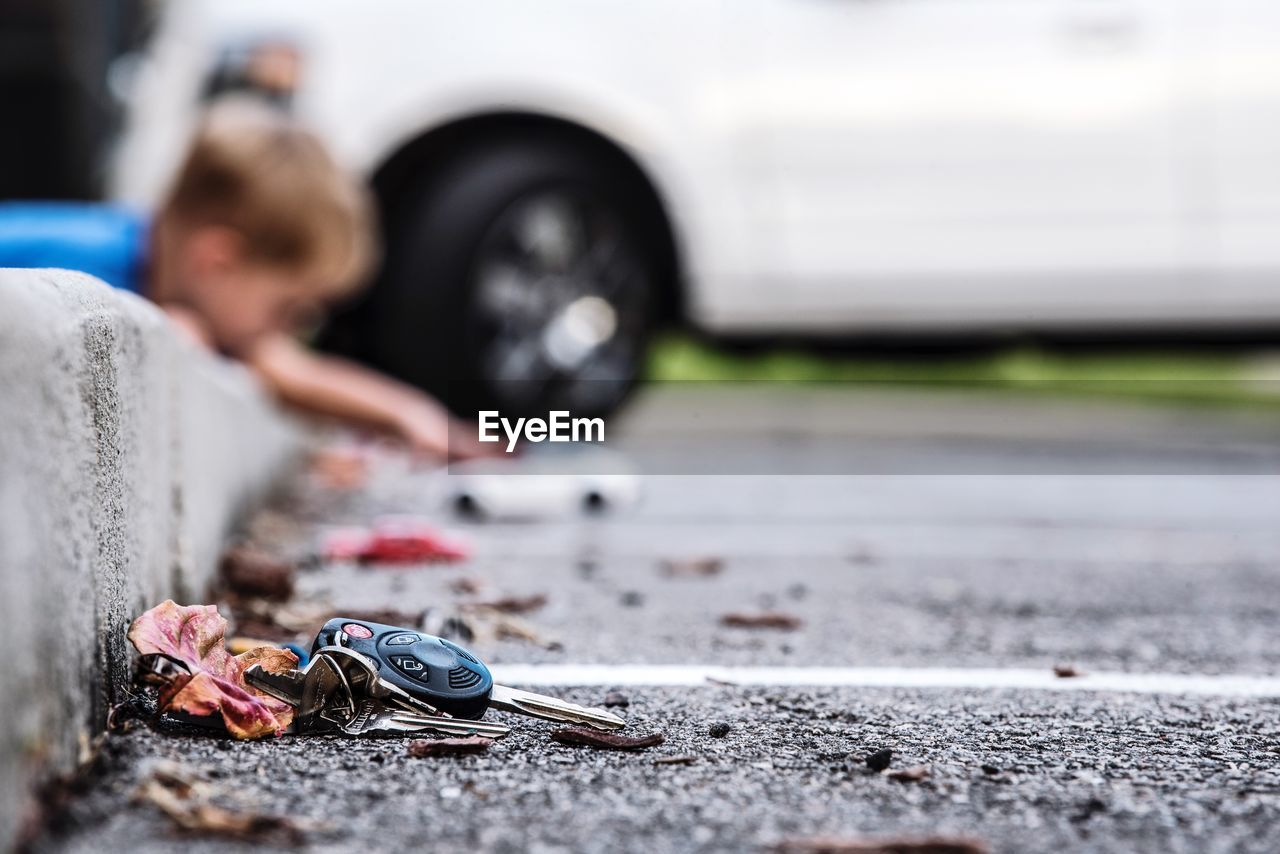 High angle view of car key on street by dry leaf