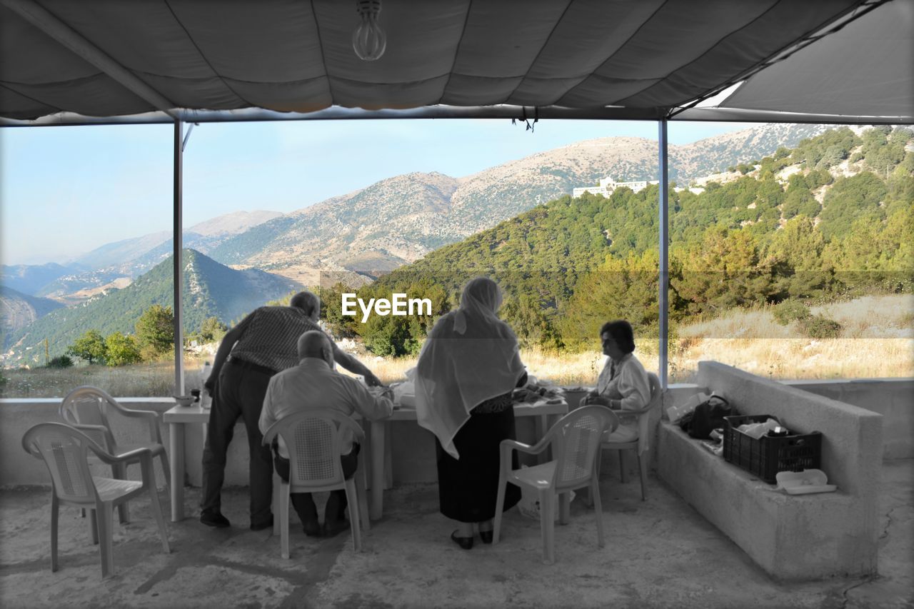 PEOPLE SITTING ON MOUNTAIN