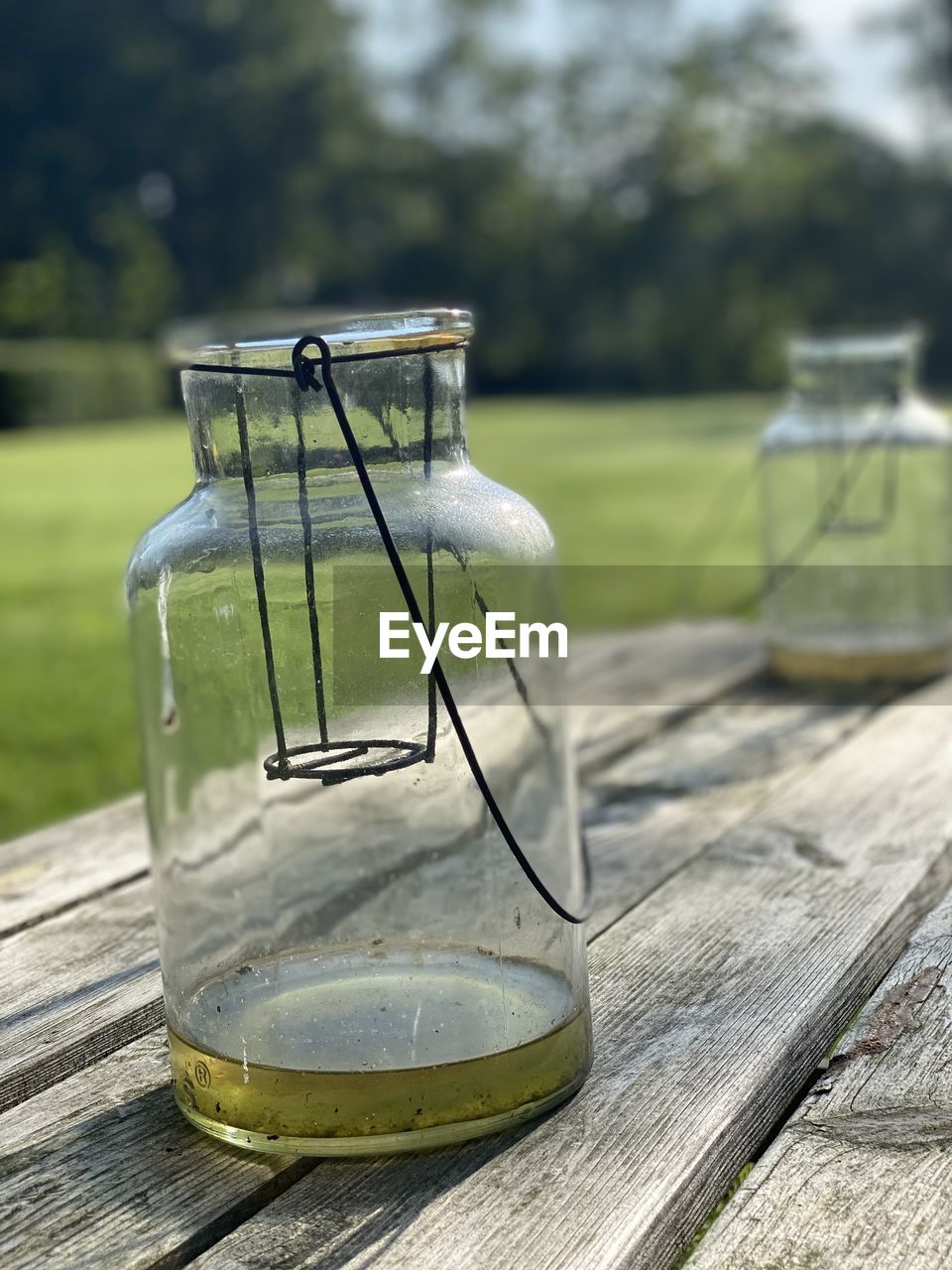 CLOSE-UP OF GLASS JAR ON TABLE BY FIELD