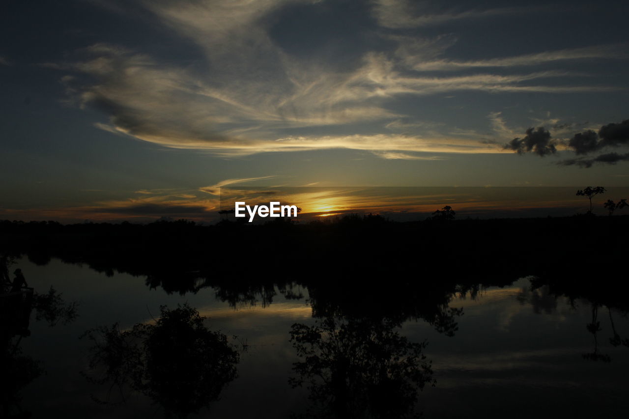 Silhouette trees reflecting on lake against sky during sunset