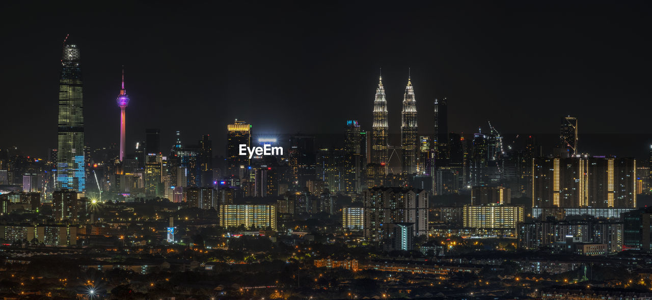 Illuminated buildings in city against sky at night