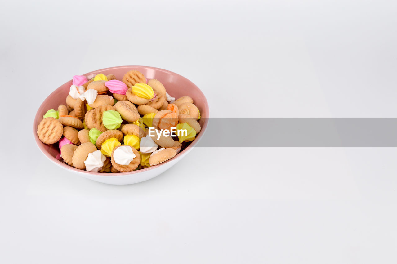 High angle view of multi colored cookies in bowl against white background