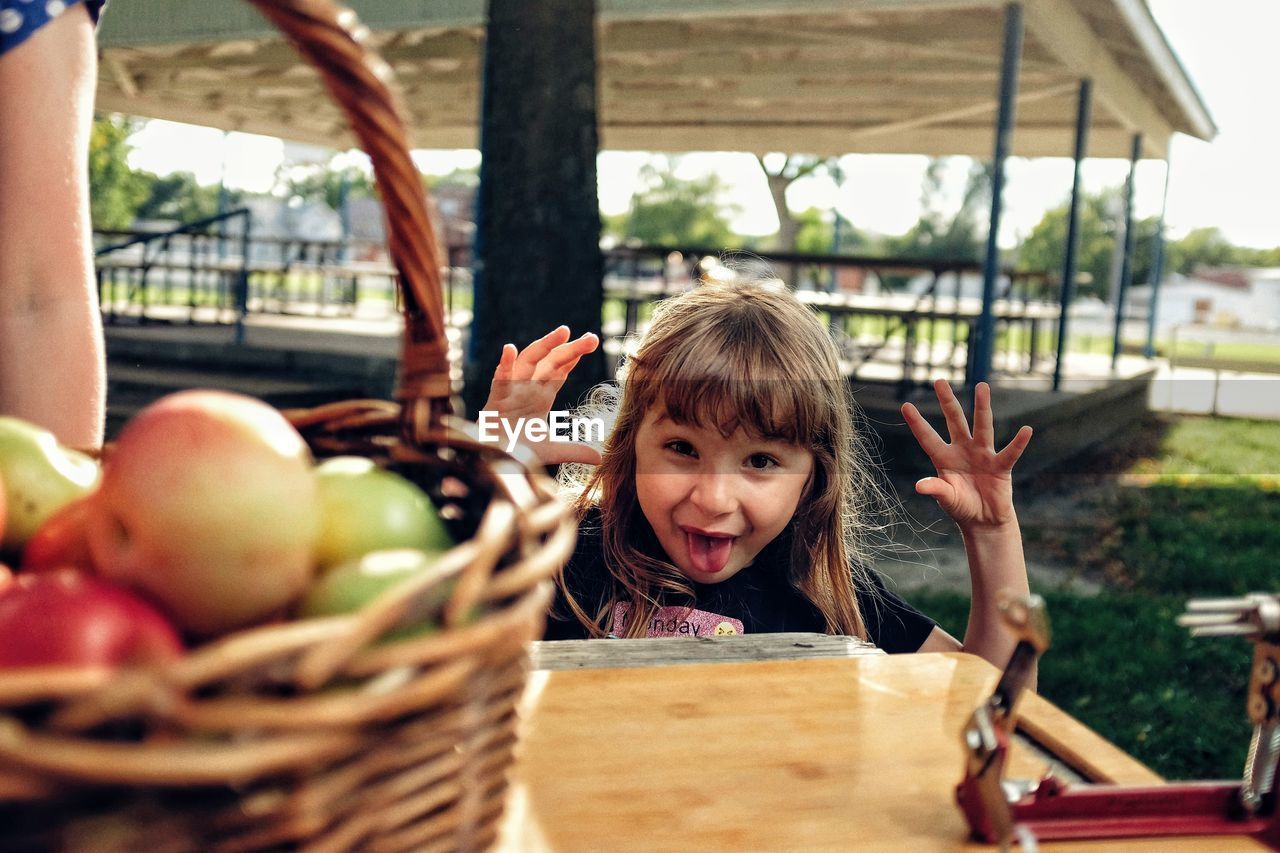 Portrait of happy girl sticking out tongue by table in park