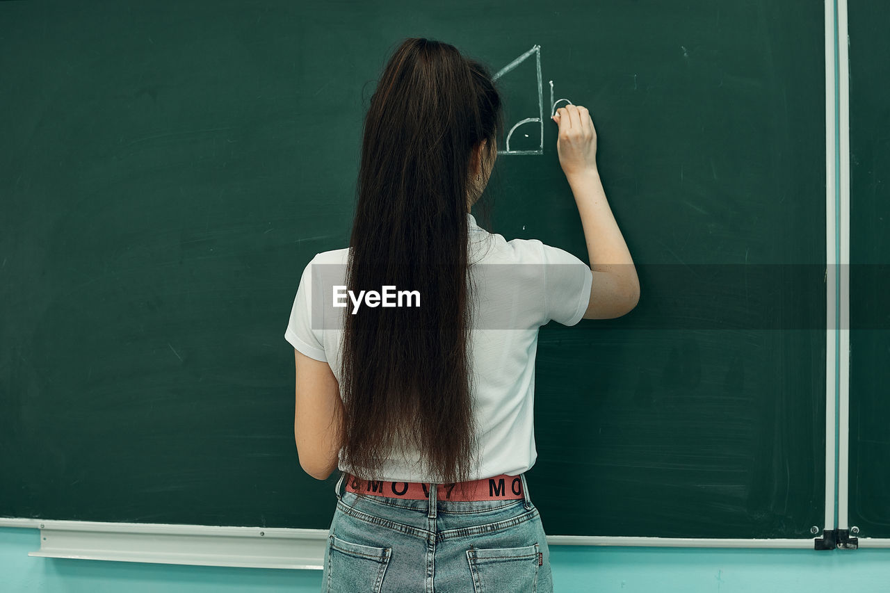 Asian high school girl solves geometry on the blackboard