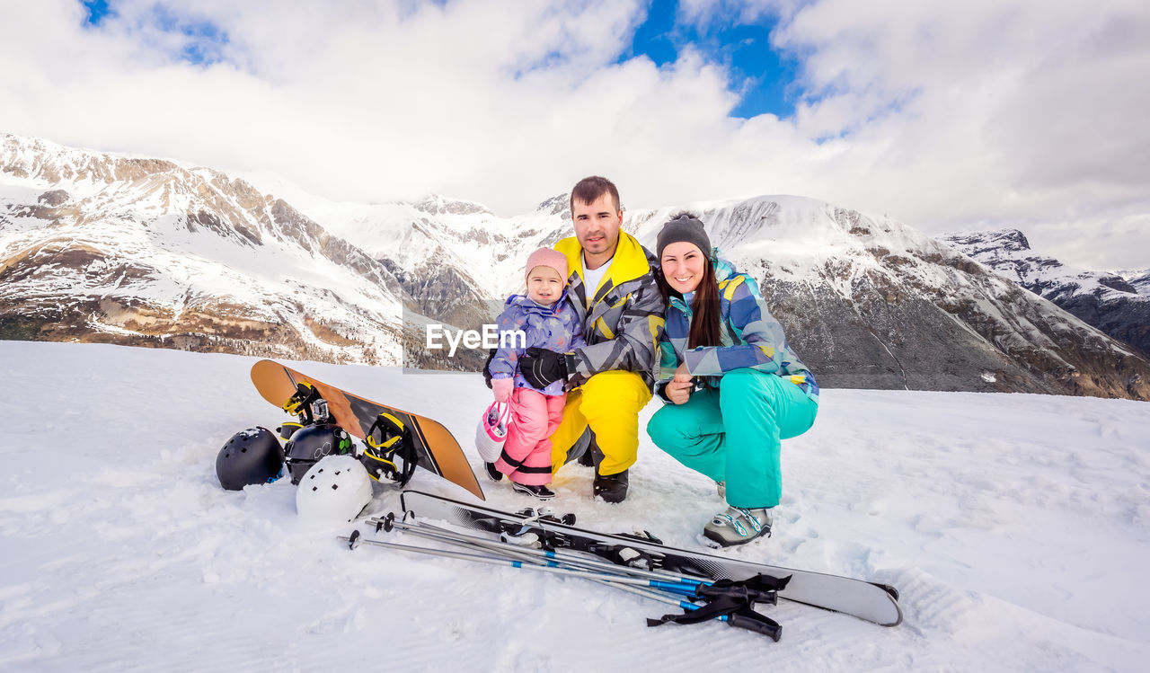 Portrait of family crouching on snowcapped mountain during winter